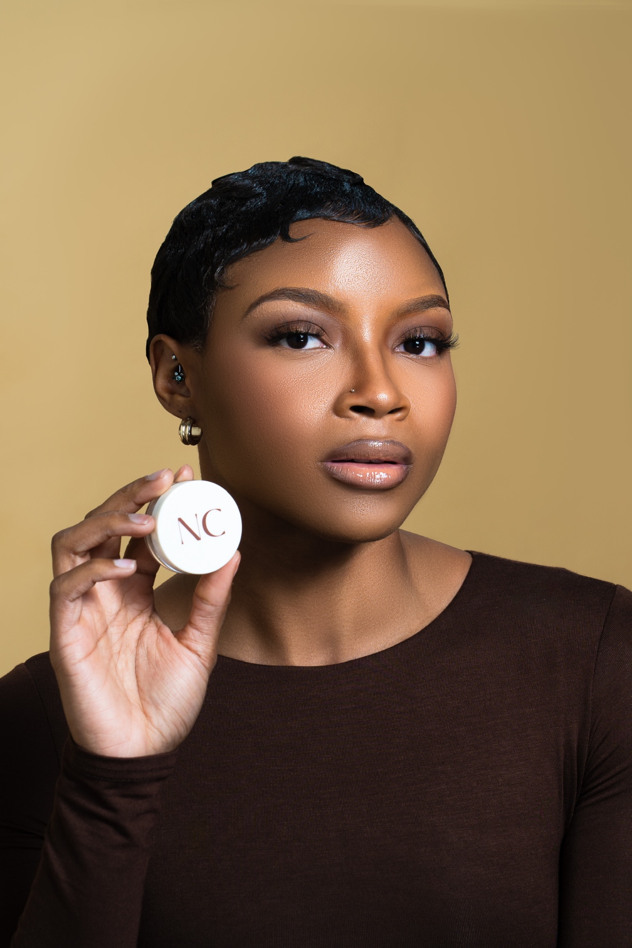 Beauty campaign portrait holding a small cosmetic jar beside the face