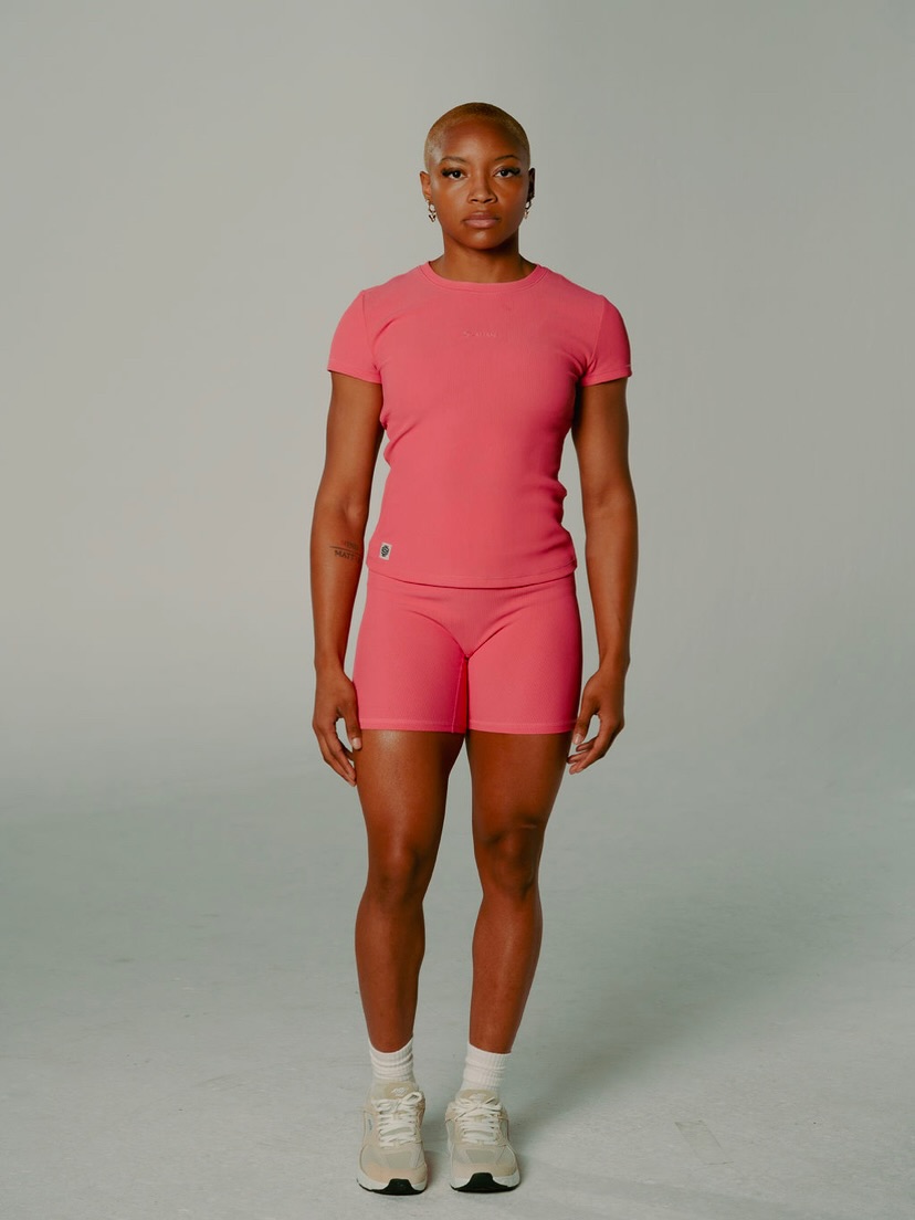 Full-length activewear shot in a coral ribbed set and sneakers