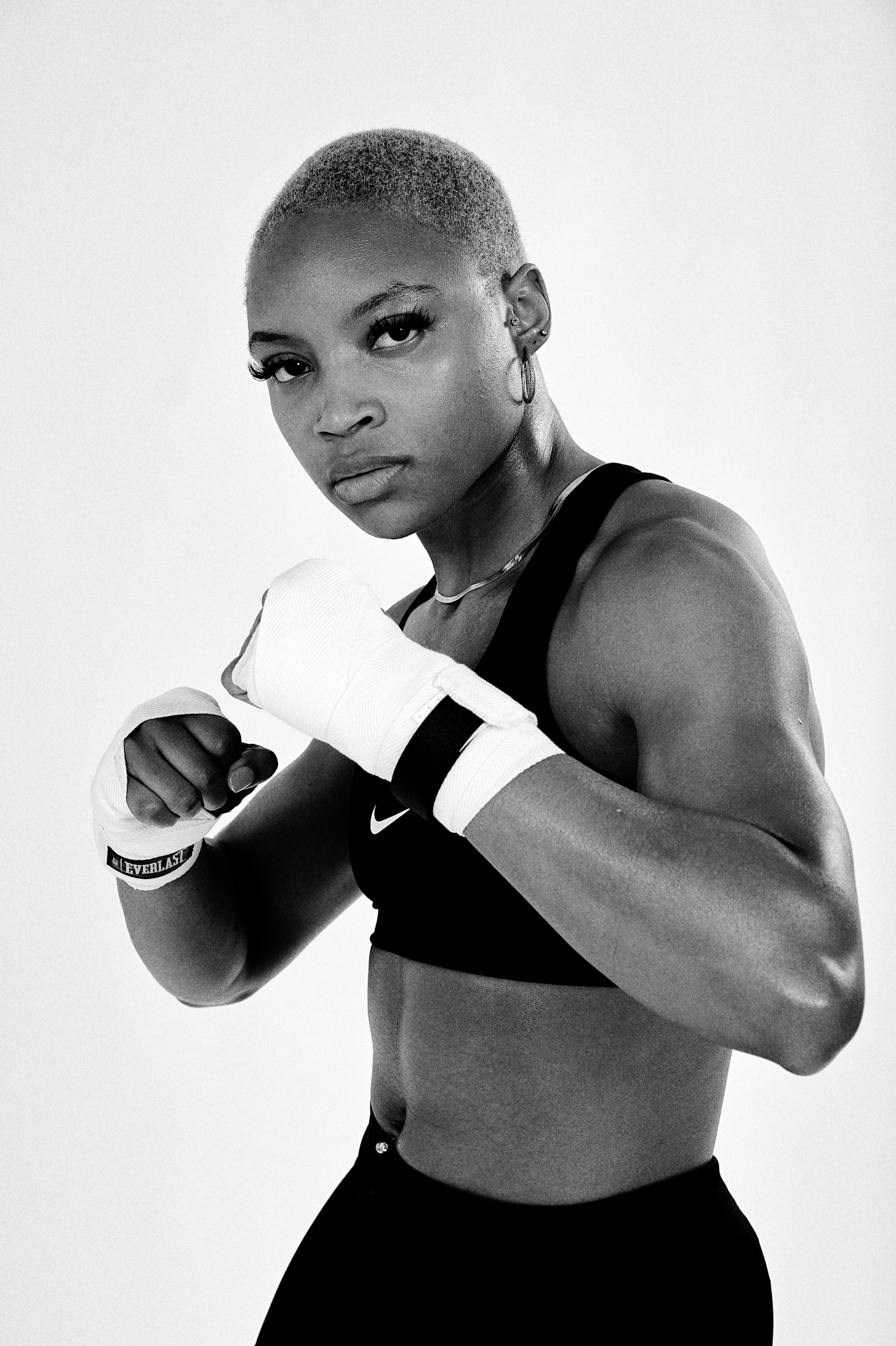 Black-and-white waist-up fitness shot in a boxing guard with wrapped hands