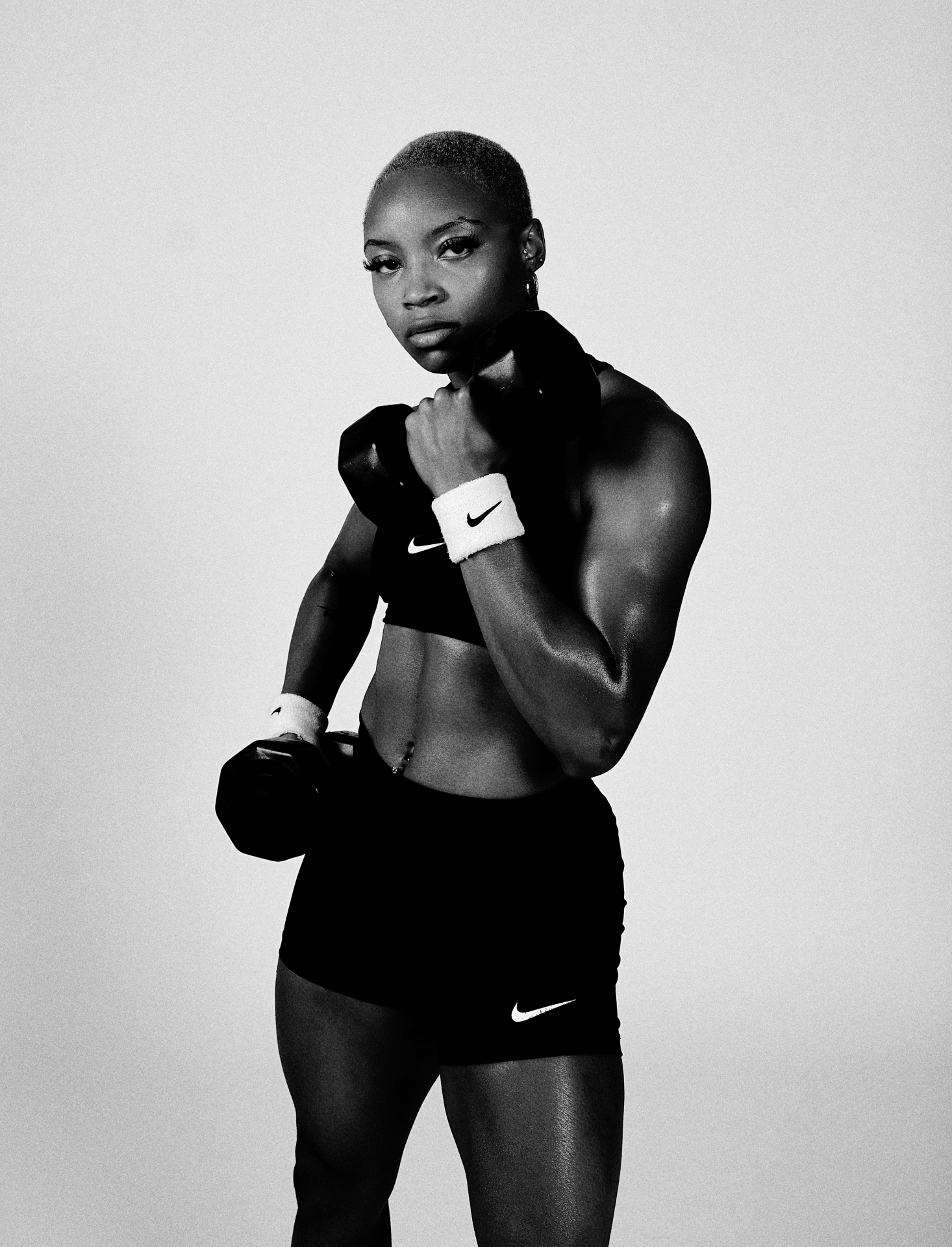 Black-and-white three-quarter fitness shot holding dumbbells