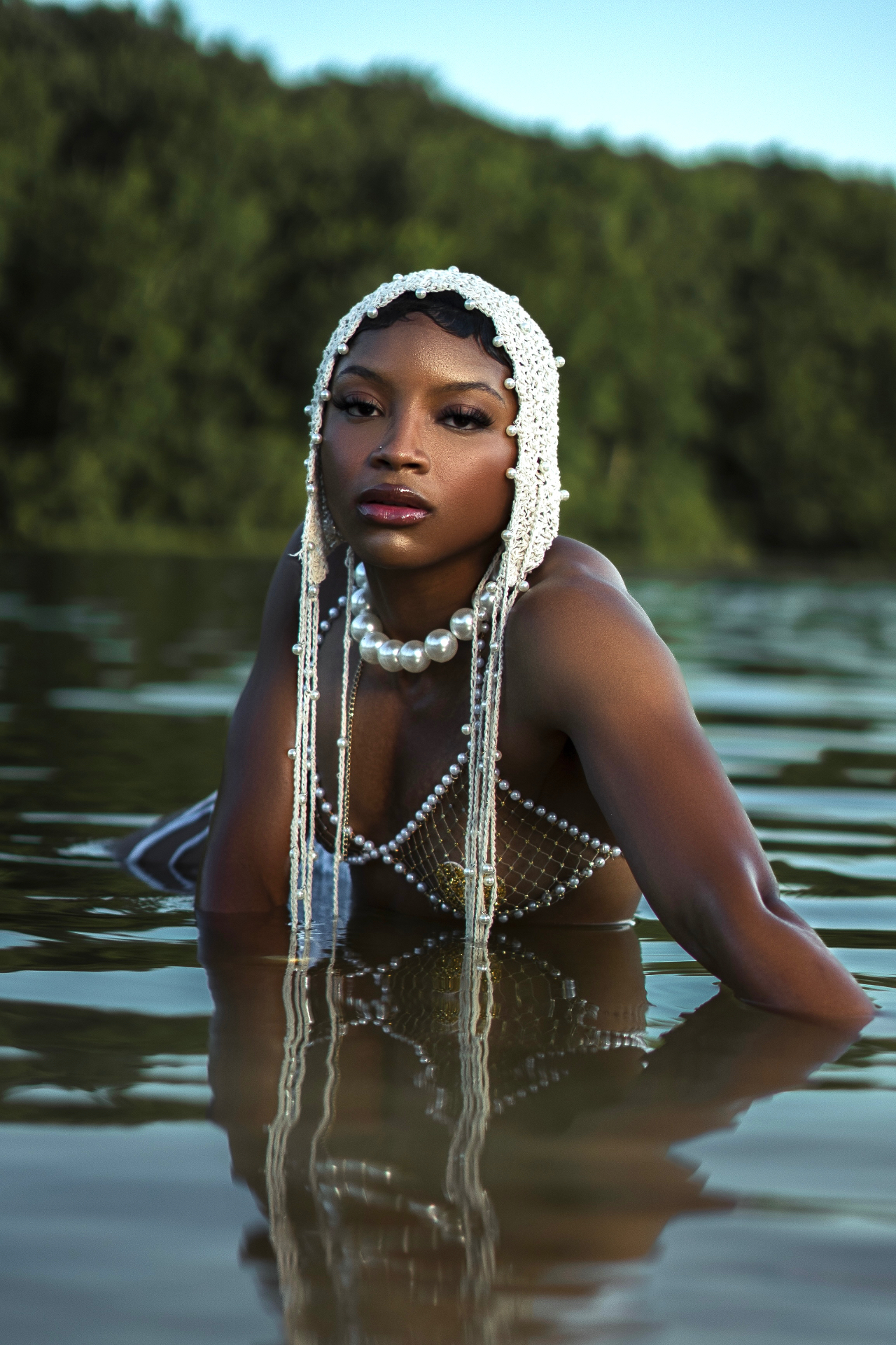 Editorial shot in a pearl headpiece and pearl net top in the water