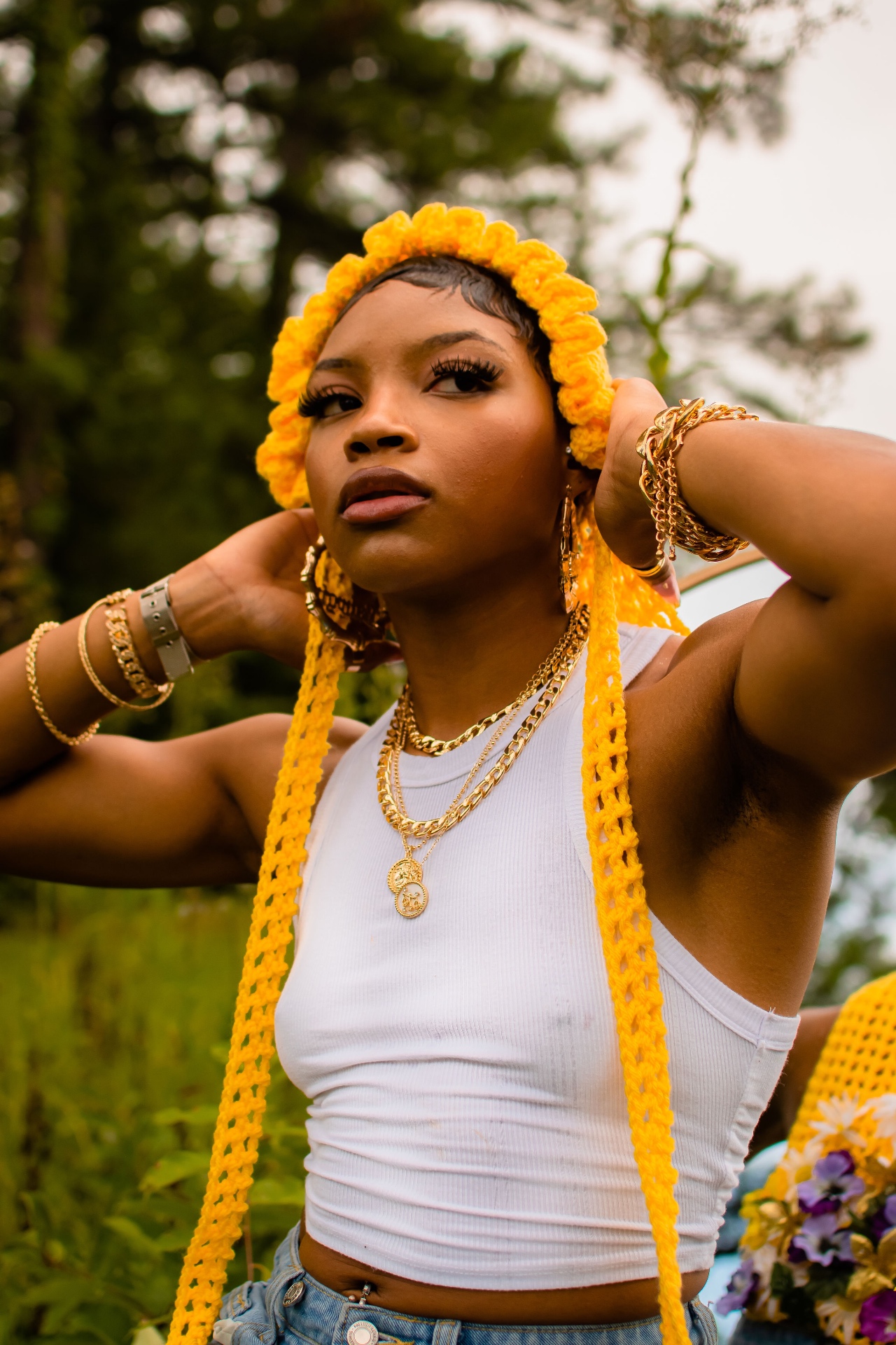 Close-up editorial shot in a yellow knitted headpiece with gold chains on the chest