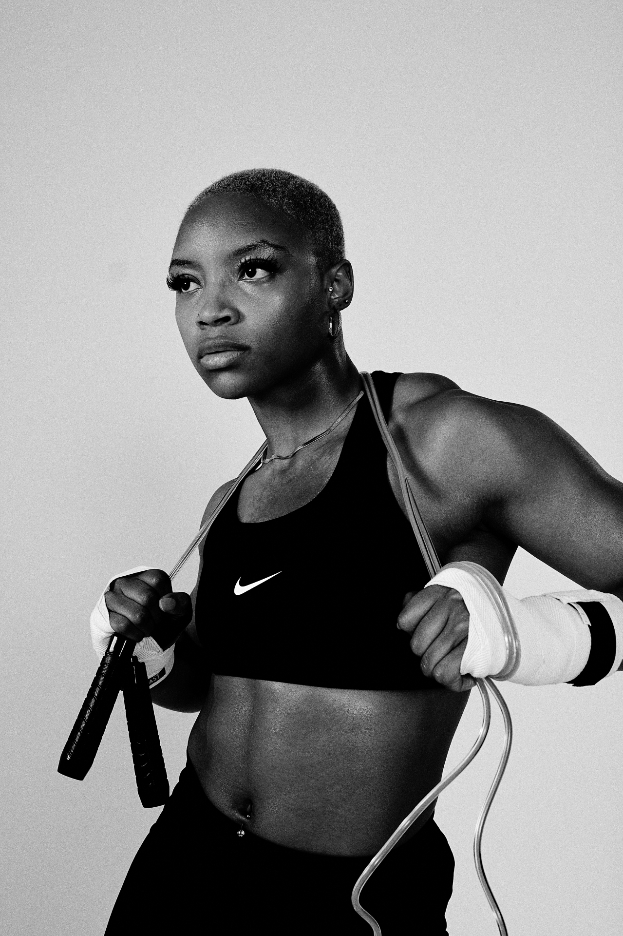 Black-and-white waist-up fitness shot holding a jump rope across the shoulders